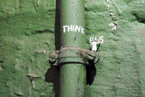 Tiny statuette of a figure writing "Think Big" on an industrial pipe